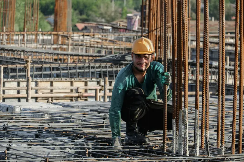 Steel fixer in a hard hat tying rebar on a slab