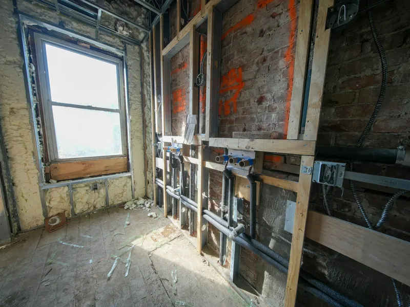 Stripped interior under construction with exposed pipes and wiring
