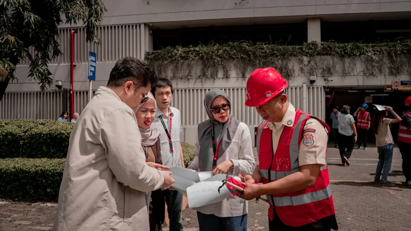 Site team in hard hats reviewing drawings together outside a building
