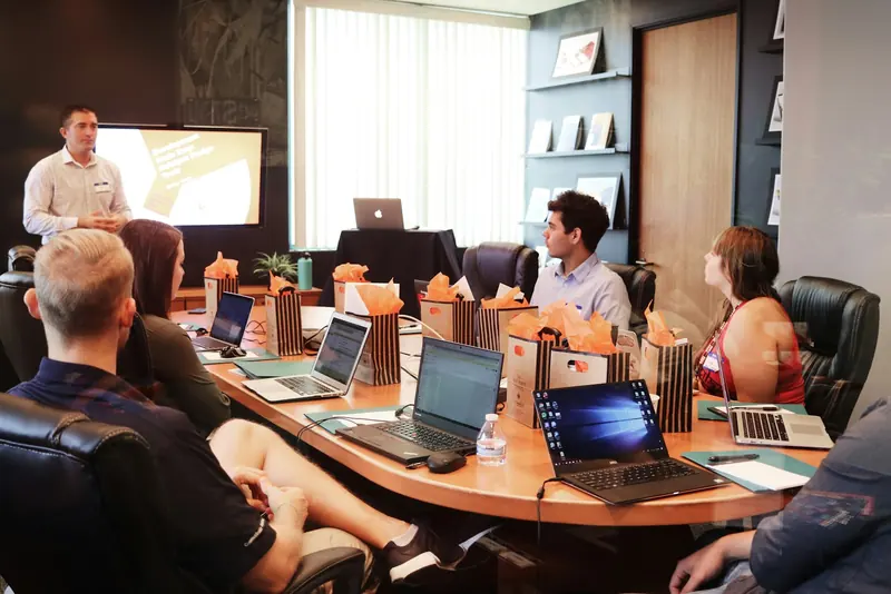 Team training session around a boardroom table with laptops
