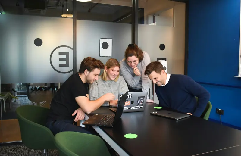 Team working together around laptops in a meeting room