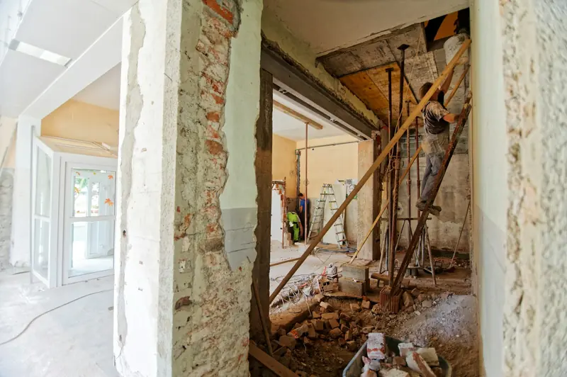 Tradesman on a ladder in a room halfway through renovation