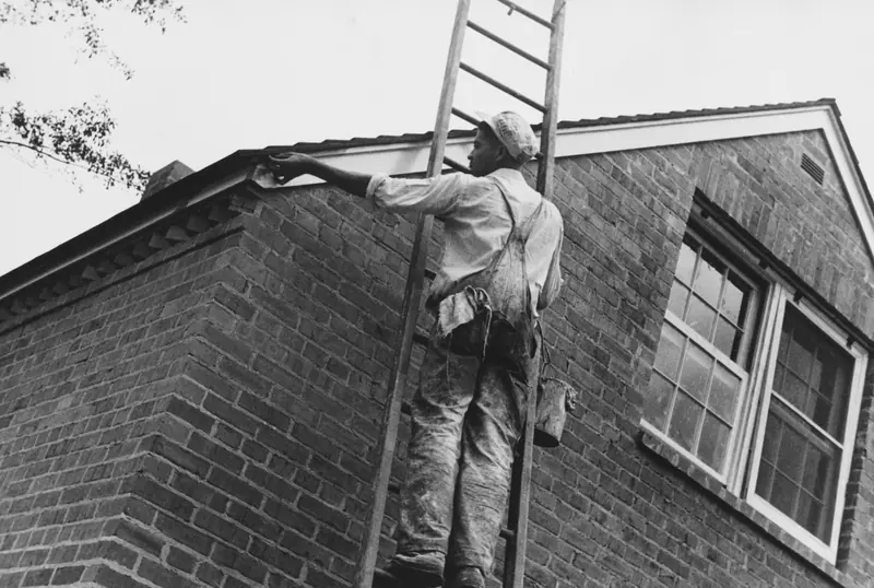 Tradesman on a ladder working on a brick house