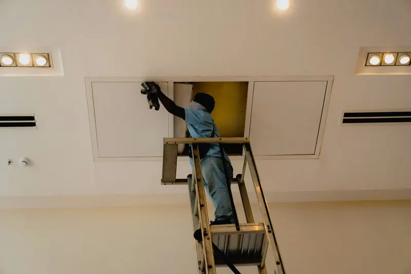 Tradesman on a stepladder working on a ceiling during a refurbishment