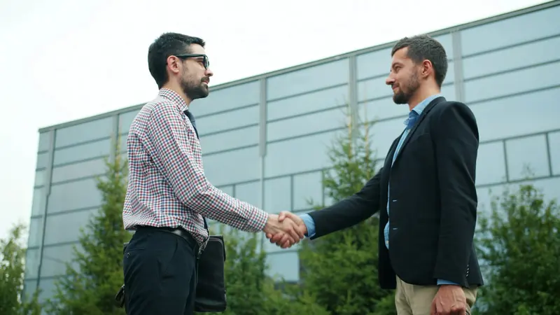 Two businessmen shaking hands outside an office building