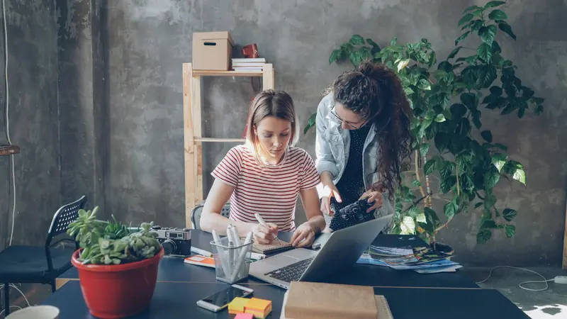 Two colleagues working on drawings at a shared desk