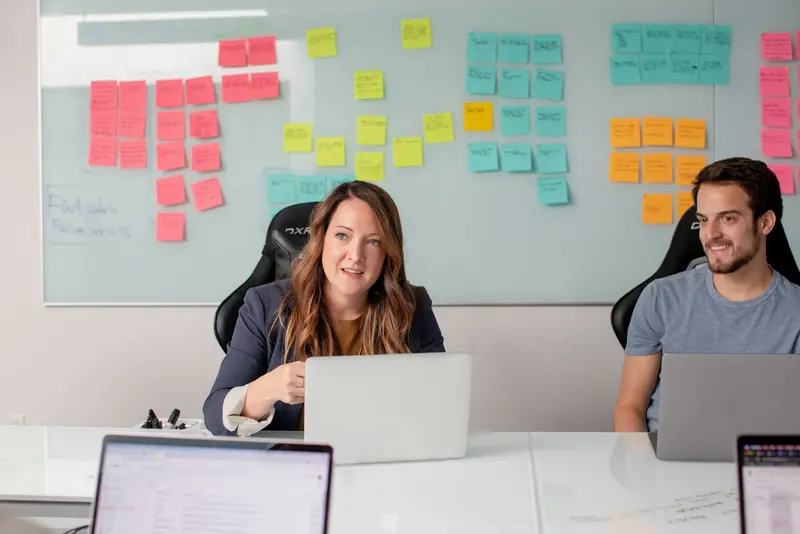 Two people in a meeting with laptops and sticky notes