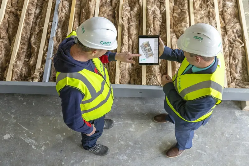 Two site managers in hi-vis reviewing plans on a tablet