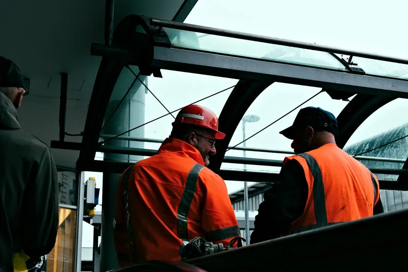 Two site workers in orange hi-vis talking on a project