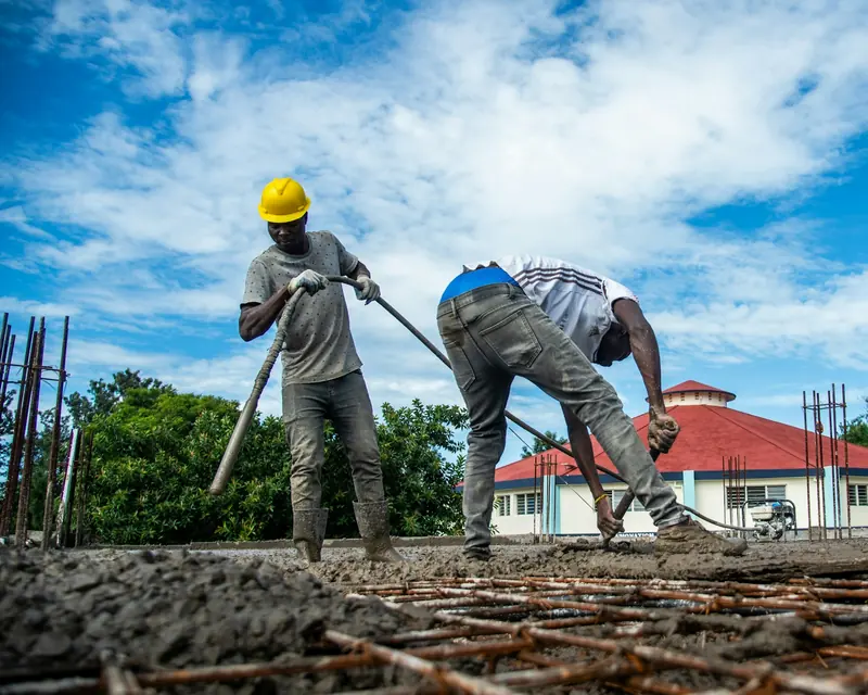 Two workers levelling concrete over rebar on site