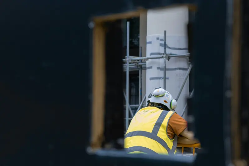 Worker in a hard hat and hi-vis framed through an opening on site