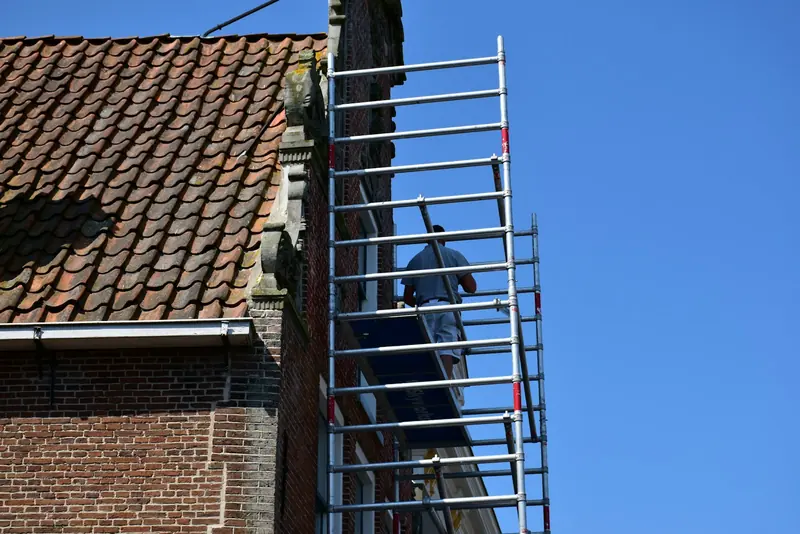 Worker on a scaffold beside a brick building