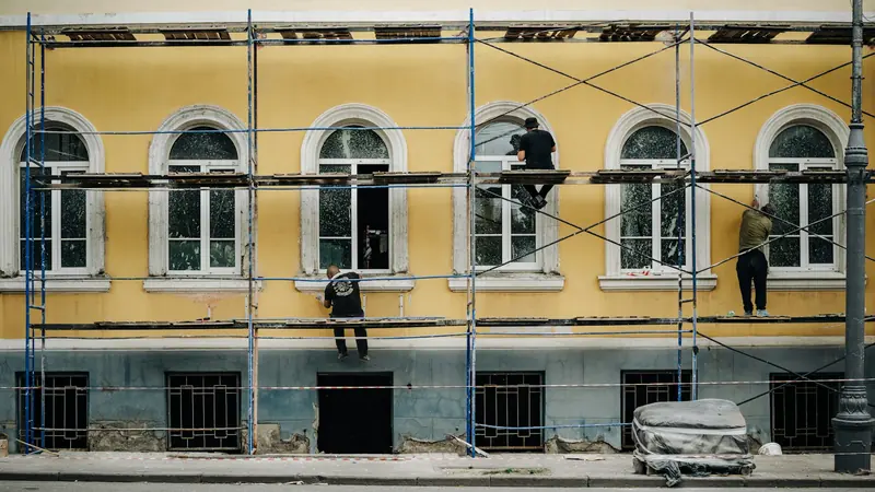 Workers on scaffolding repairing and painting a building facade