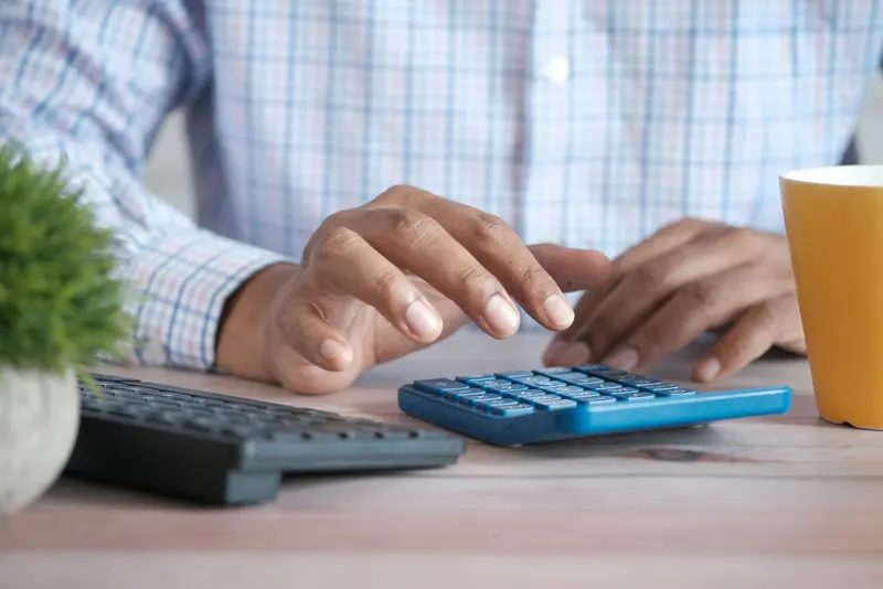 Hand using a calculator at a desk