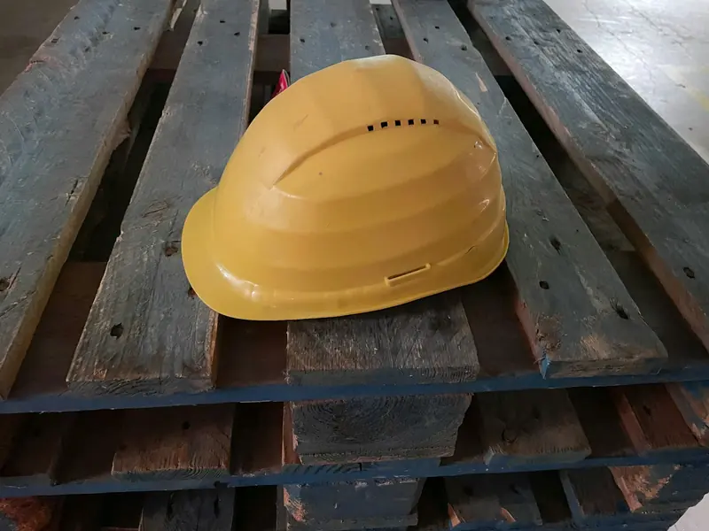 Yellow hard hat resting on a timber pallet