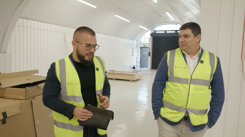 Two site managers in hi-vis talking inside a converted railway-arch unit