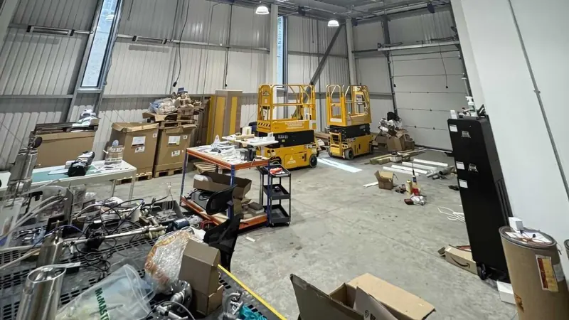 Warehouse unit cluttered with equipment and scissor lifts before refit